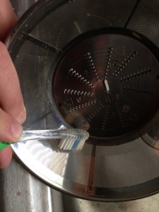 using a toothbrush to clean the screen of the GE Juicer