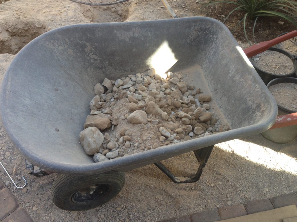 wheel barrow of rocks removed while digging holes in Las Vegas desert dirt